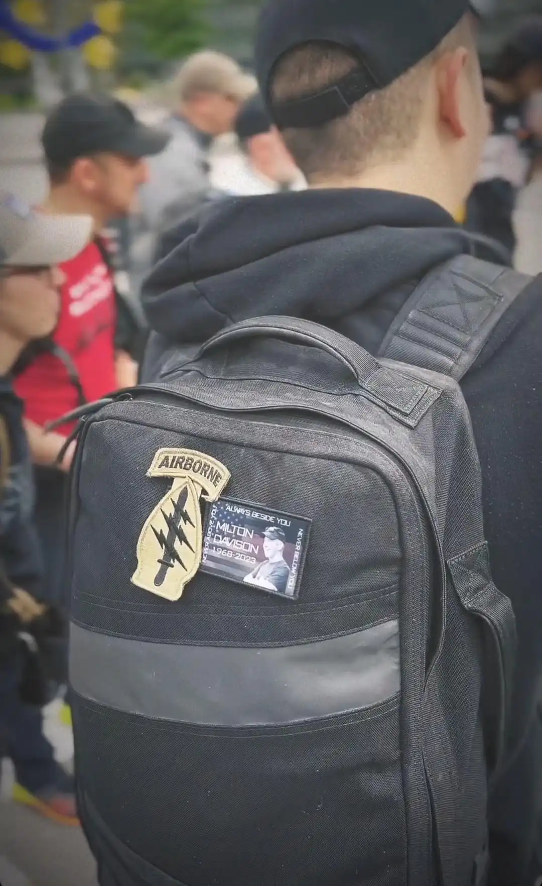 Image: Close-up view on a ruck on a participant's back; ruck with an Airborne patch and a commemorative patch for Milton Davison
