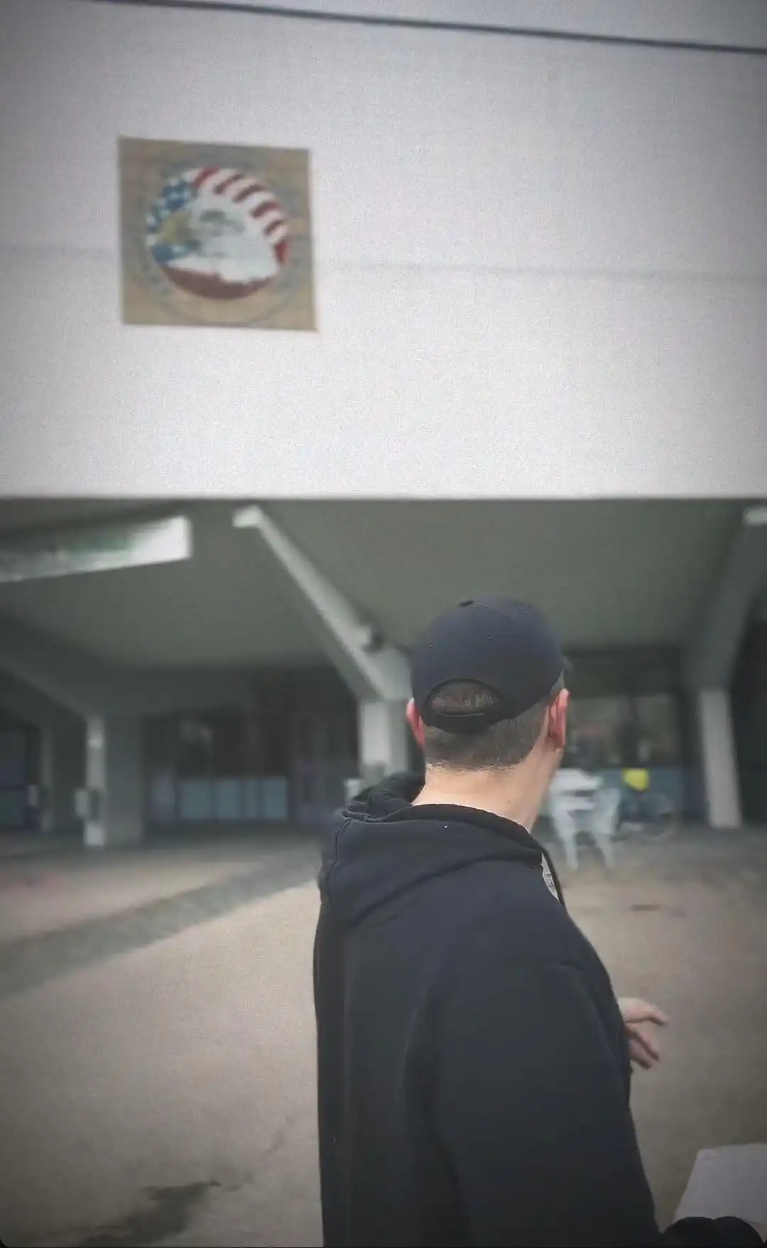 Image: Milton's son is seen with his back turned towards the camera, gesturing towards the entrance of the high school his dad went to.